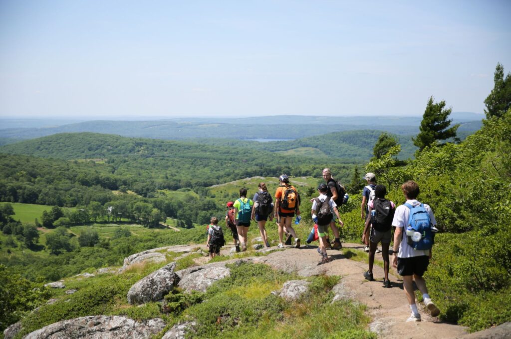 Campers hike along a scenic ridge, demonstrating the physical and mental health benefits of summer camps.