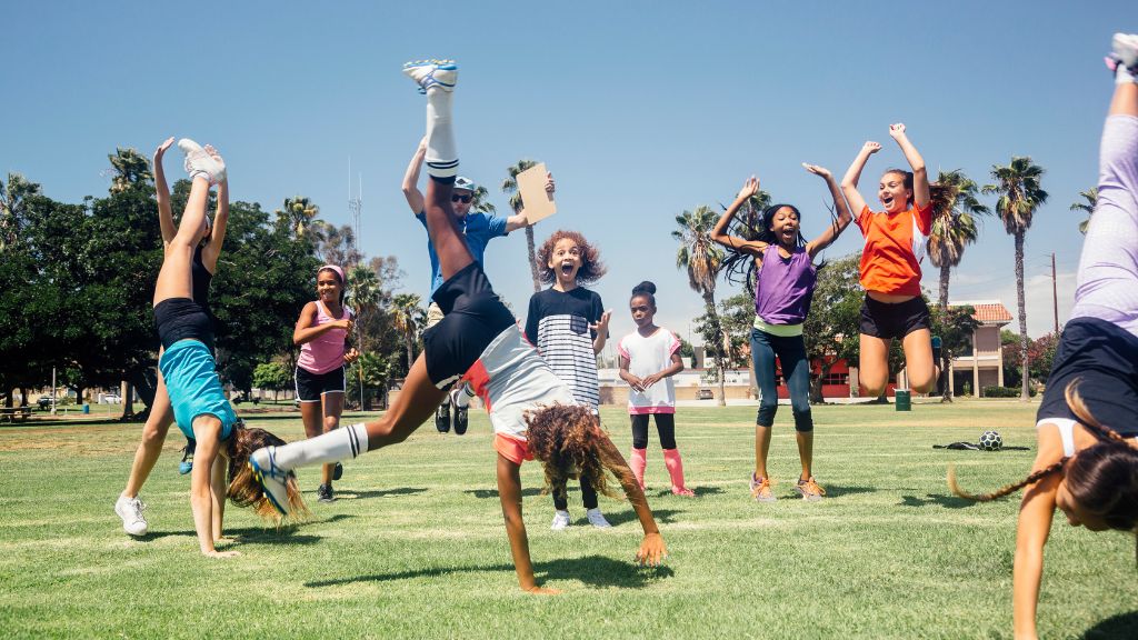 Kids run, jump, and do cartwheels across a sunny field, showing energy, teamwork, and joy during outdoor activities at Sports Camps.