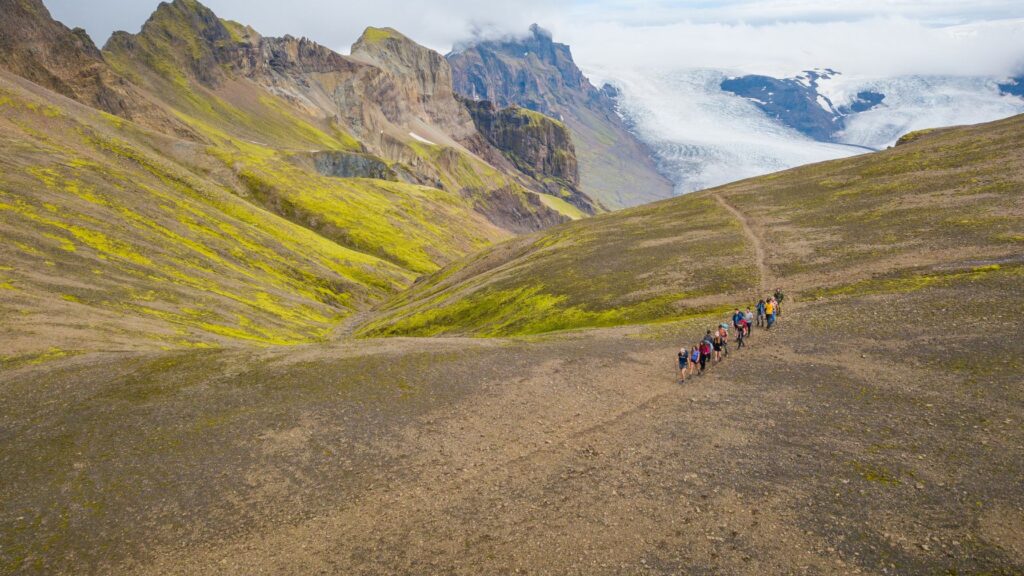 A group of campers hiking through a vast alpine landscape, symbolizing the variety of summer camp experiences and how they can differ in setting and intensity.