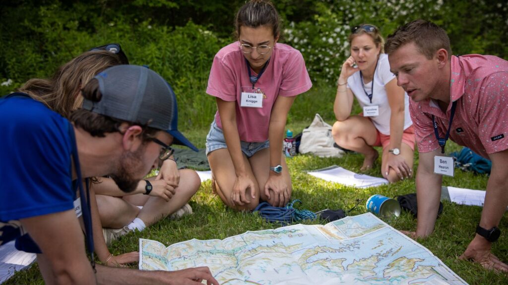 Camp staff reviewing a map and materials together, preparing answers for common parent and camper FAQs about summer camp.