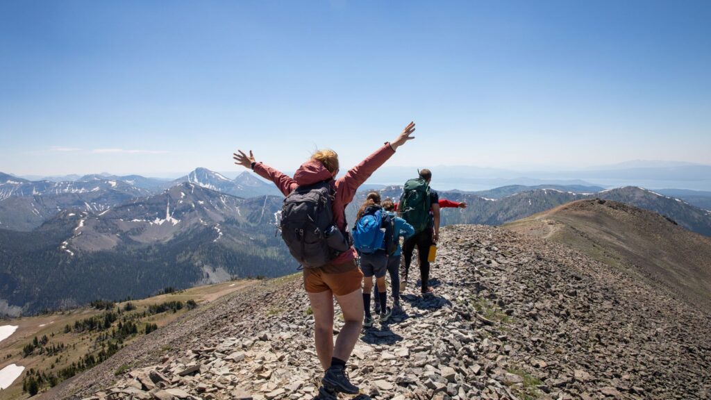 Campers hiking along a mountain ridge with backpacks, showcasing packing essentials for summer camp adventures.