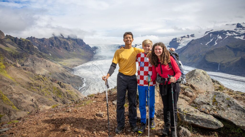 Three teen campers pose together during a mountain hike, building confidence and friendships in a new social setting.