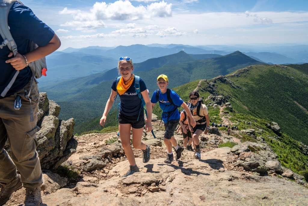 Overland campers hiking a rocky mountain trail during an adventure camp trip