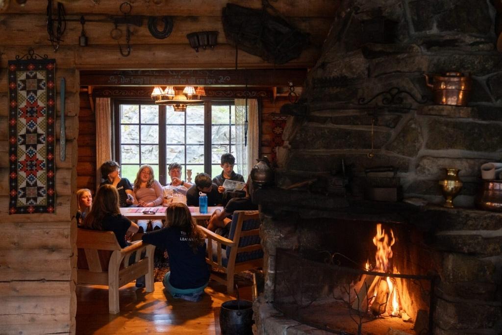 Overland campers gathering inside a rustic lodge with a stone fireplace