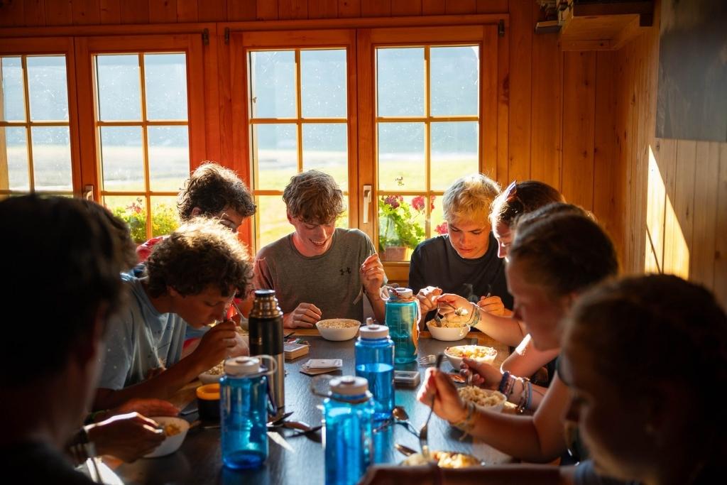 Overland campers sharing a meal together inside a rustic mountain lodge