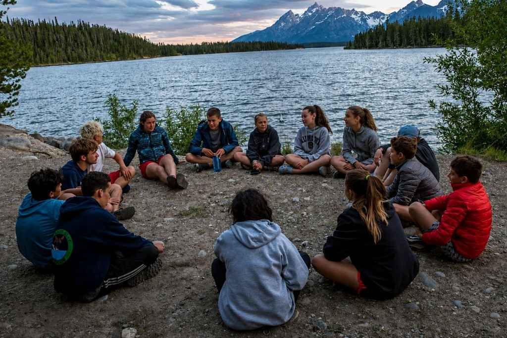 Overland campers gathered in a circle beside a mountain lake