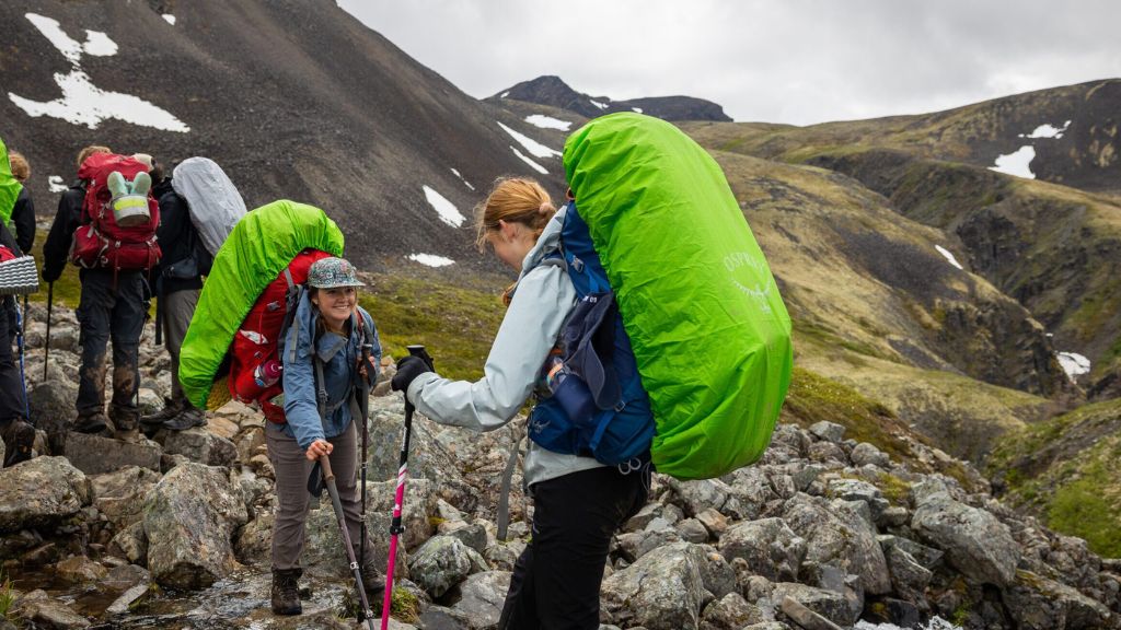 Summer campers backpacking together through rocky mountain terrain during a group adventure