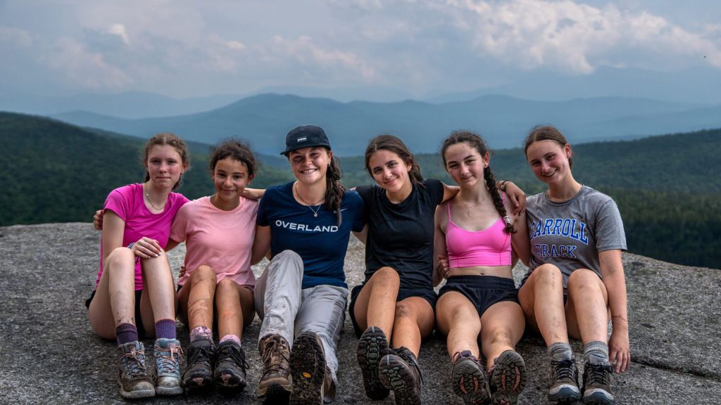Teens and an Overland leader resting at a mountain overlook during the New England Explorer trip